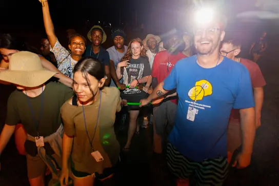 A smiling leader among campers at an evening event
