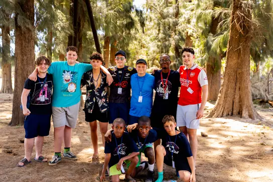 A group of boys with their arms around each other in the shade