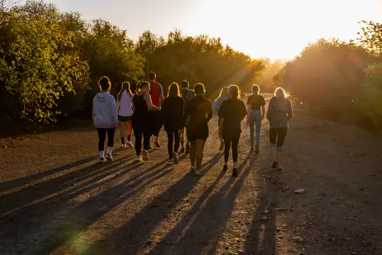 Campers walking along a dirt road at sunset